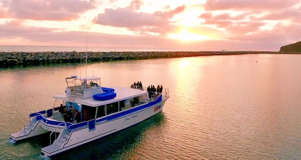 Boat with people on calm water during sunset.