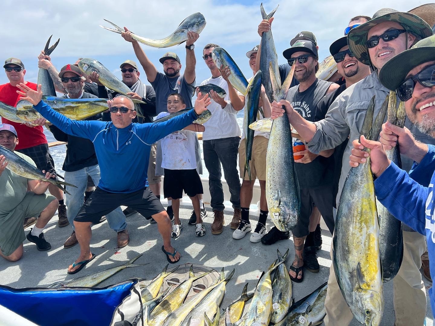 Group of people on a boat holding and displaying fish with excitement.