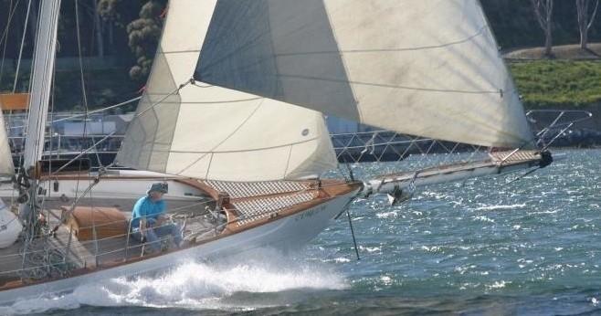 Sailboat with person onboard navigating through waves at sea.