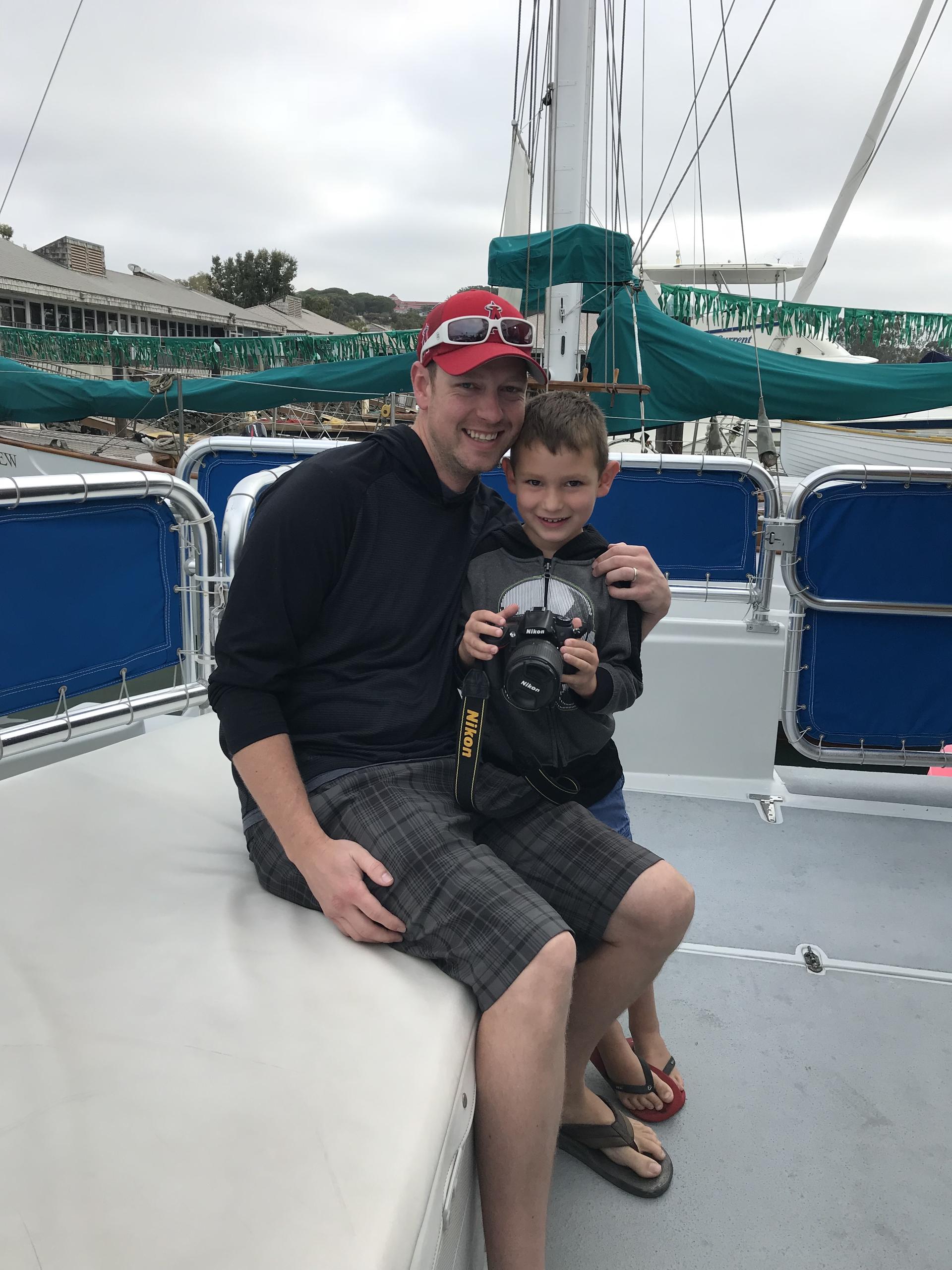 Man and child on a boat, child holding a camera.