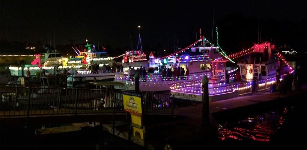 Boats decorated with colorful lights at night on a calm body of water.