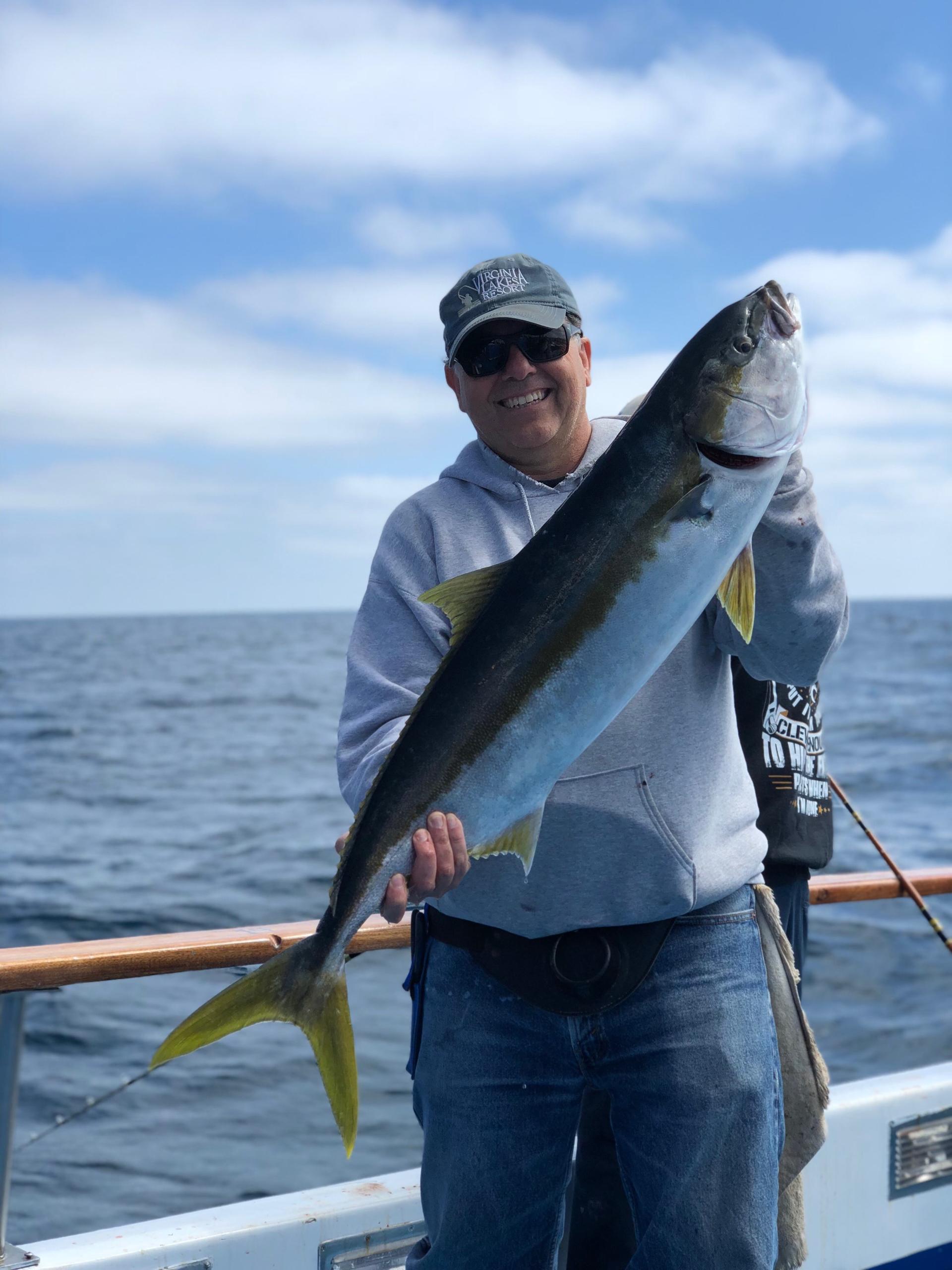 Person on boat holding a large fish with ocean in the background.