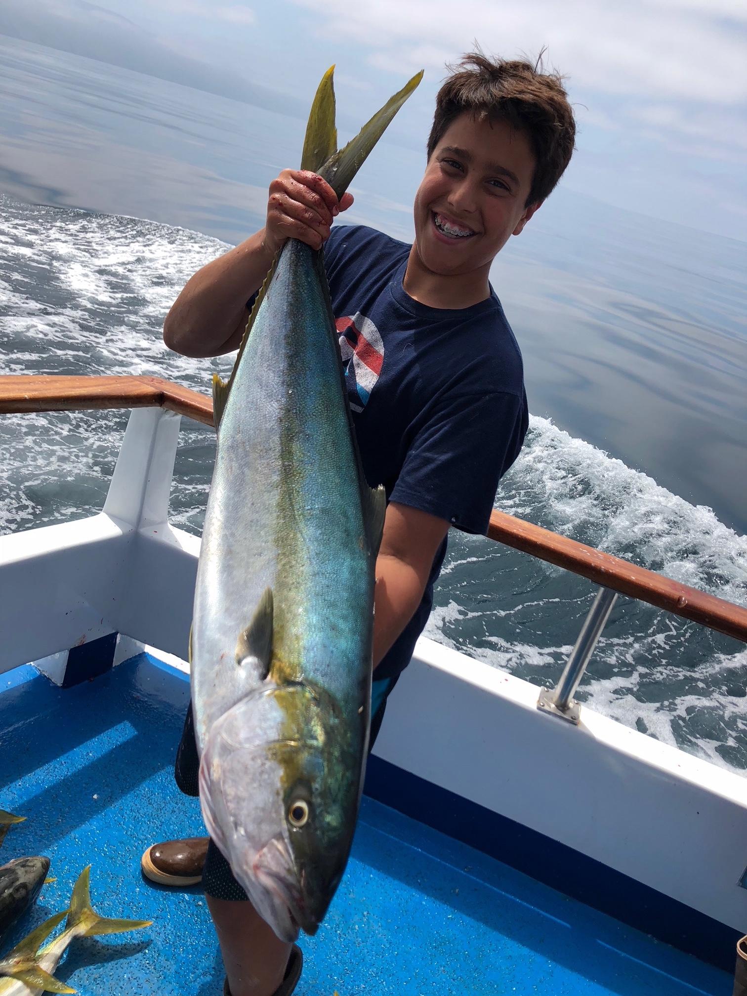 Person on boat holding a large fish with ocean in the background.