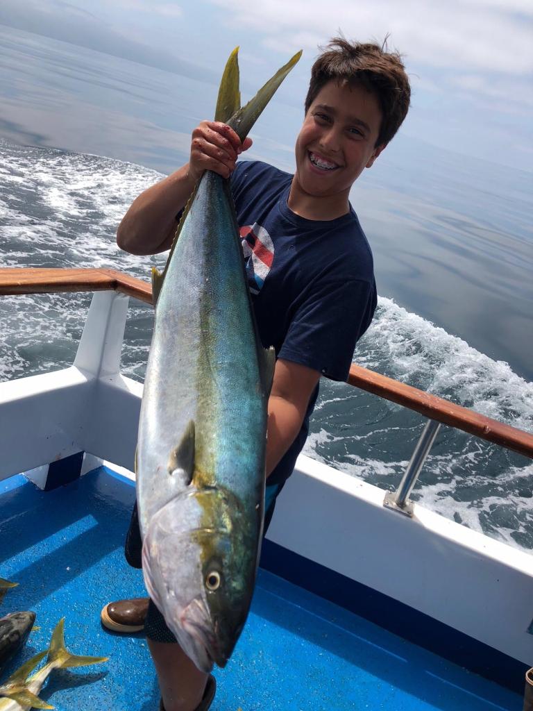 Person on boat holding a large fish with ocean in the background.