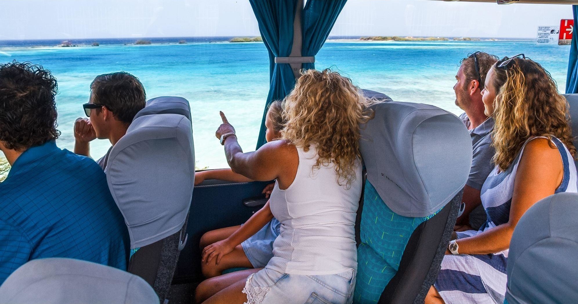 Tourists enjoying ocean view from a bus window.