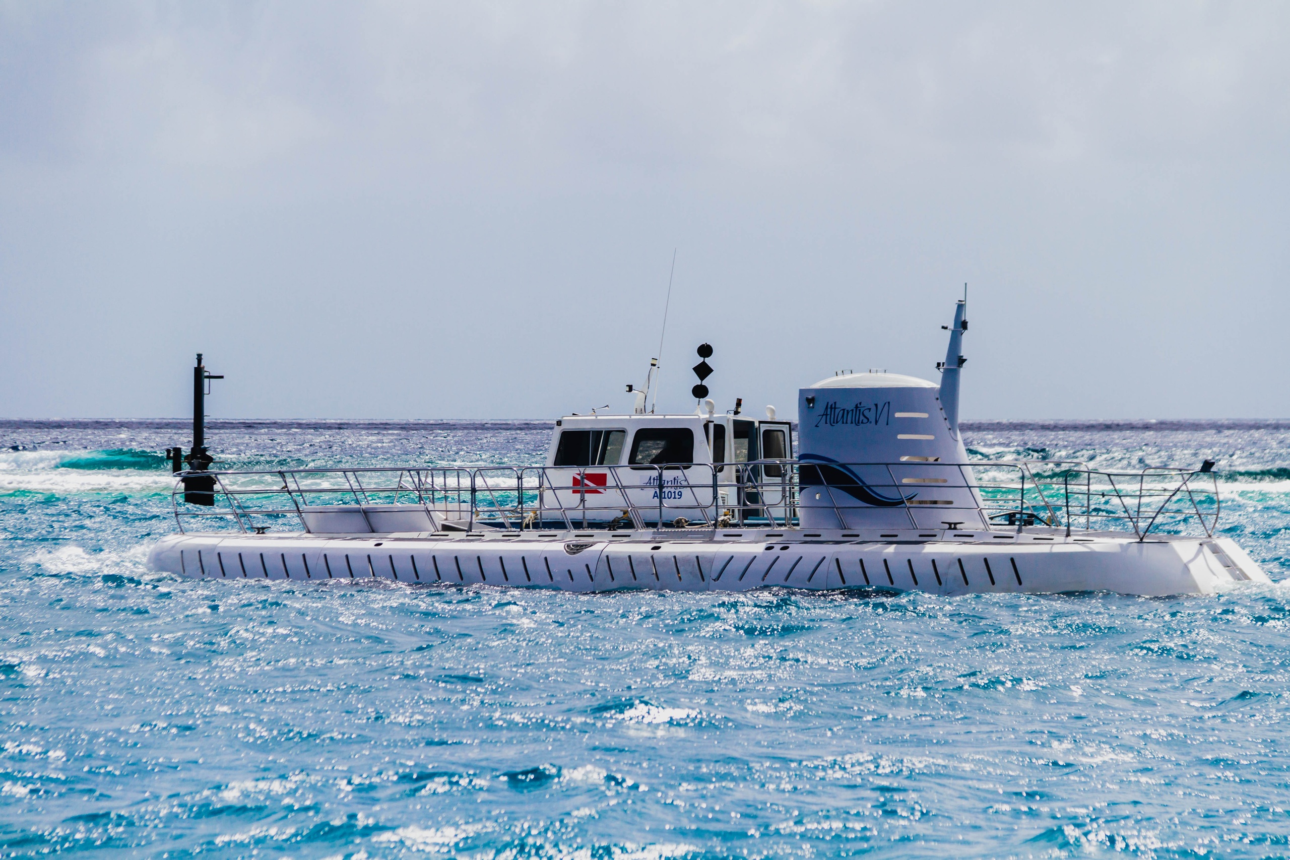 White submarine partially submerged in blue ocean waters.