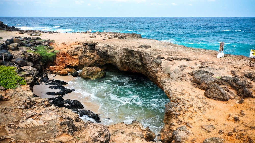 Rocky coastline with natural arch and ocean waves.