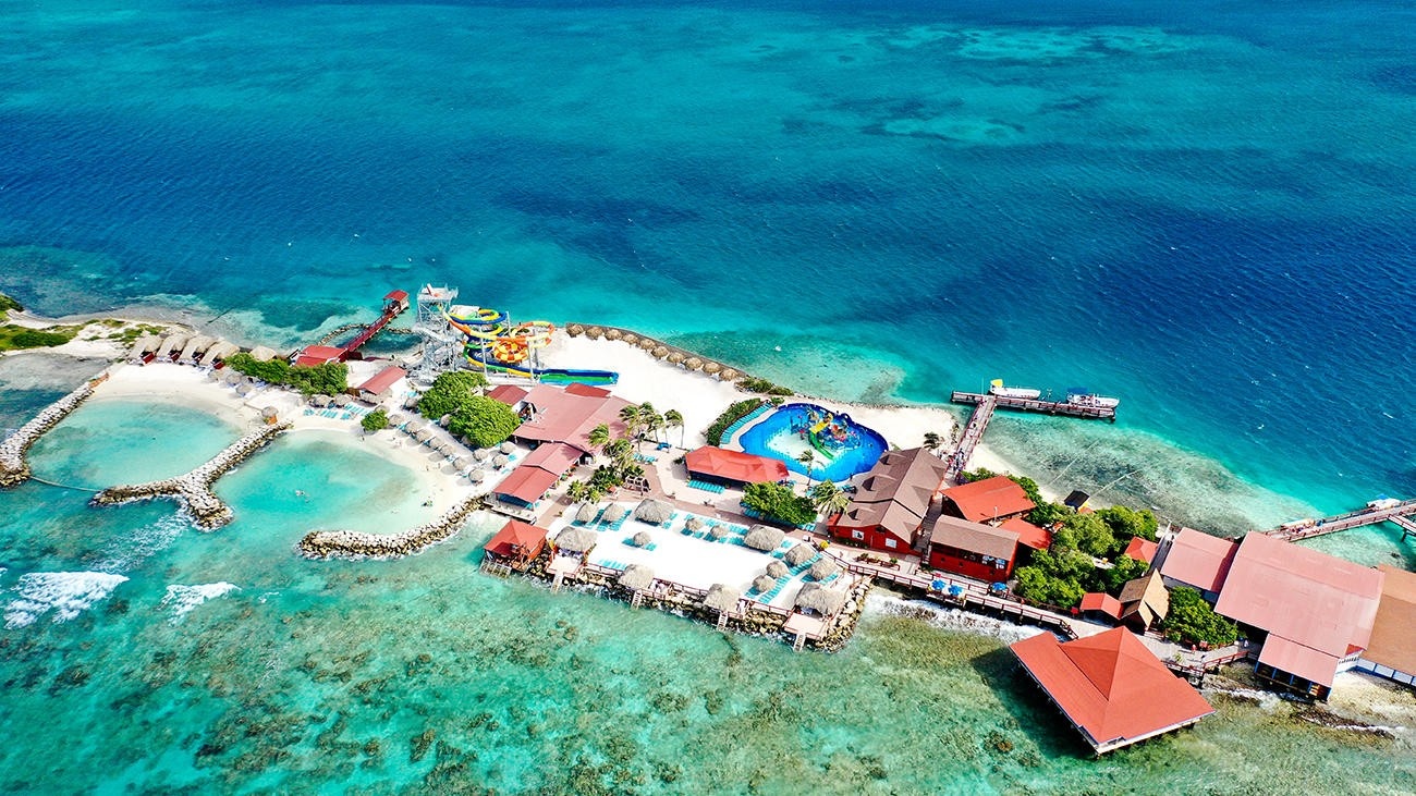 Aerial view of beach resort with pools and coastal landscape.