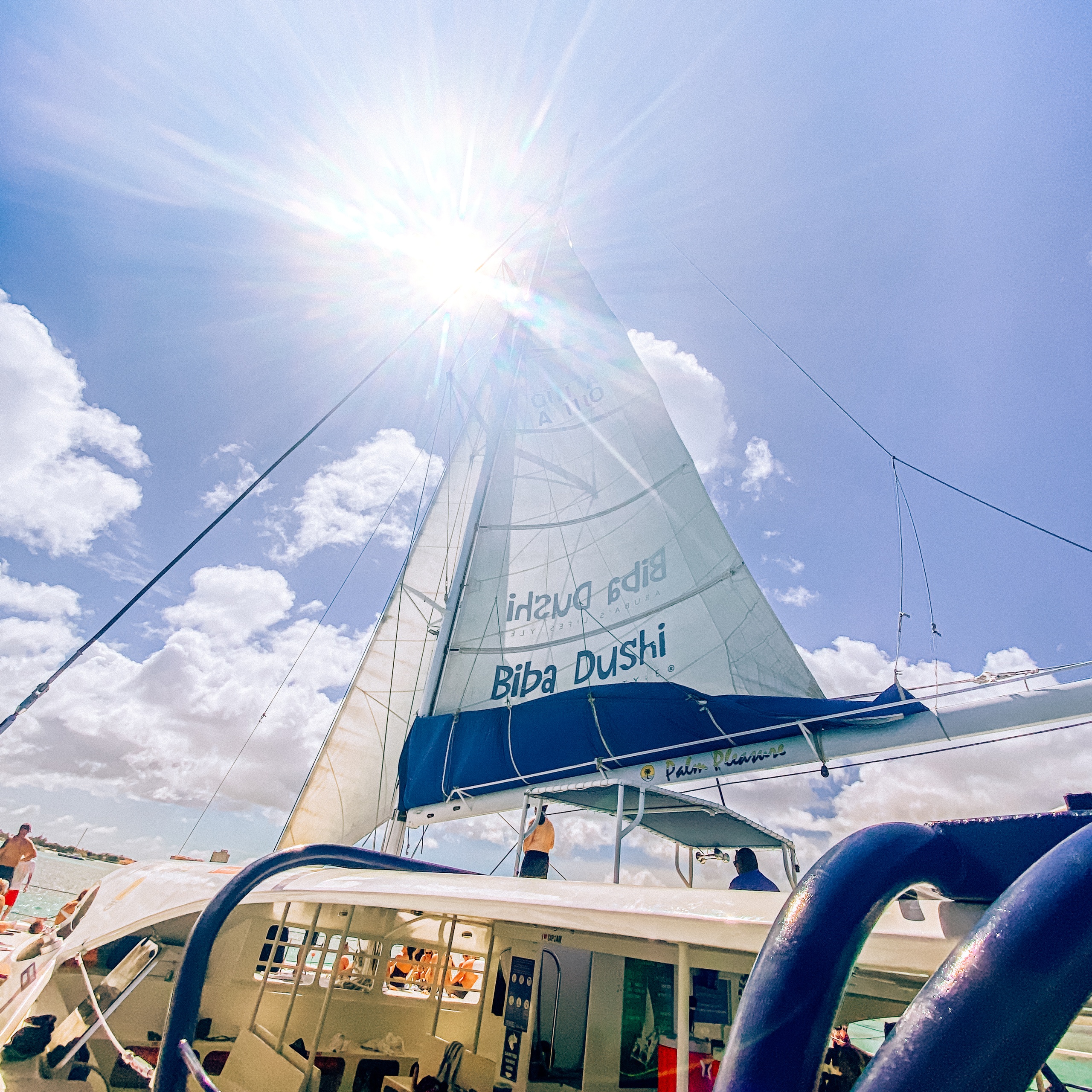 Sunlit sailboat with passengers, bright sky, and sleek design.
