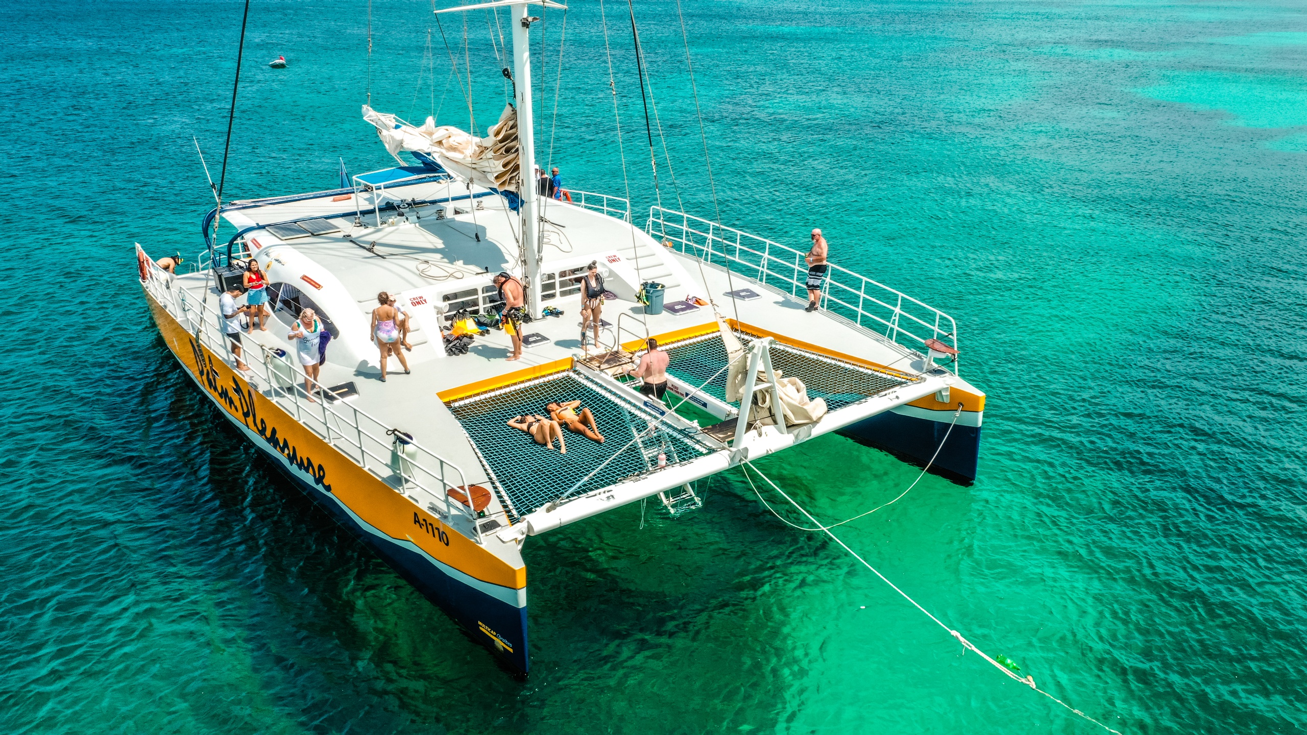 People relaxing on a catamaran in clear turquoise water.