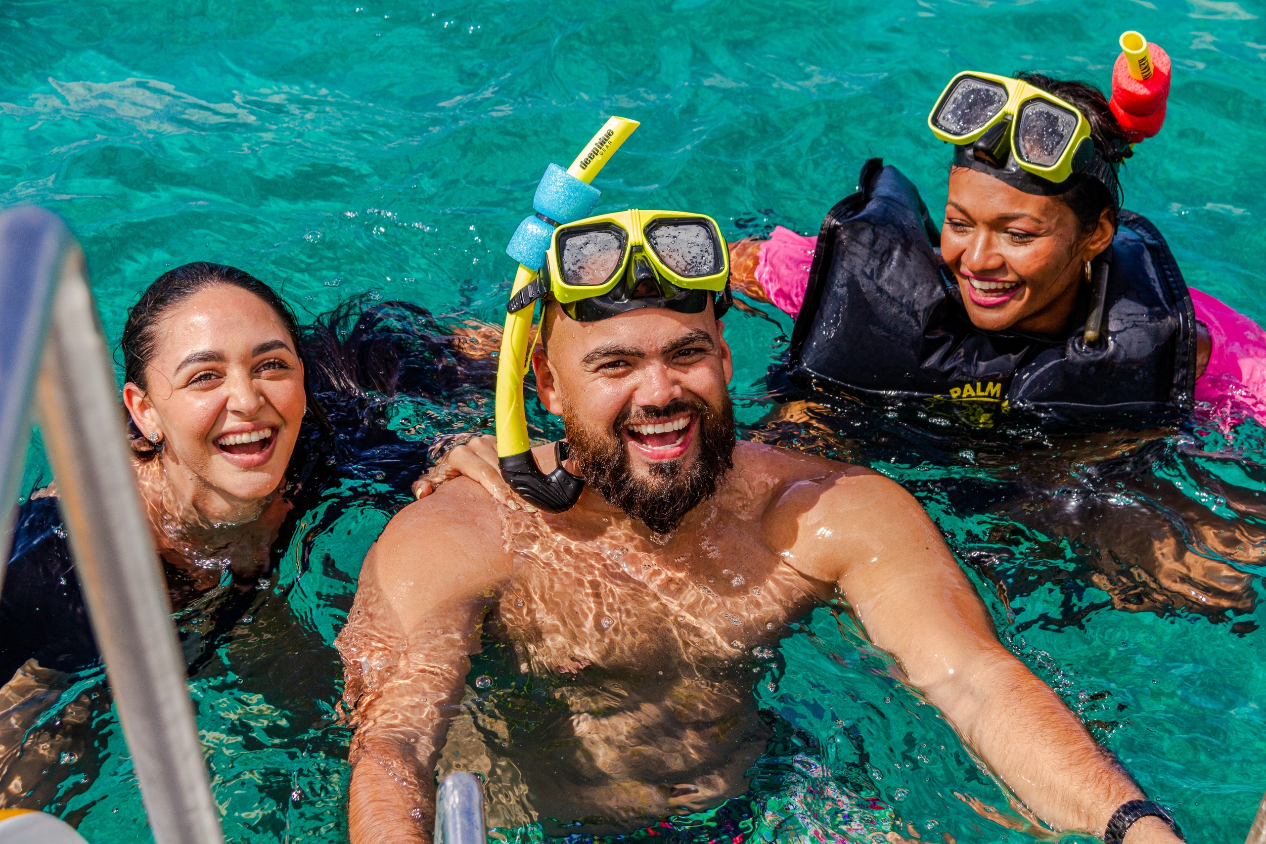 Three people smiling in the water with snorkeling gear.