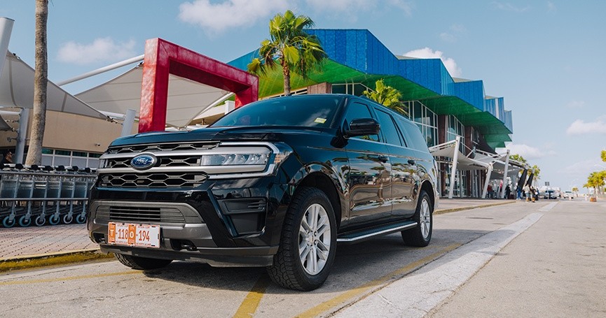 Black SUV parked near a modern building with geometric design and palm trees.