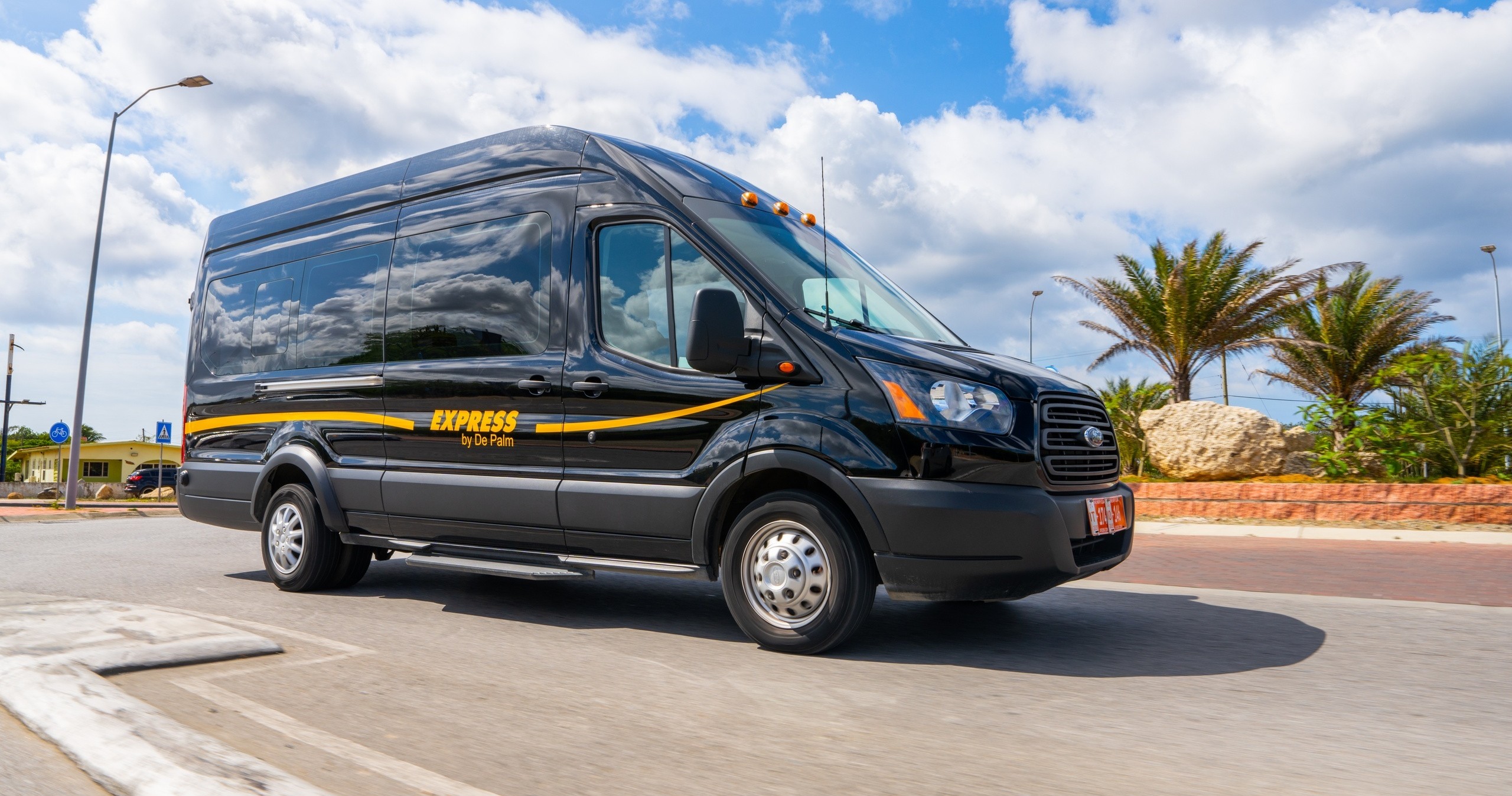 Black van labeled 'Express' driving on road with palm trees in background.