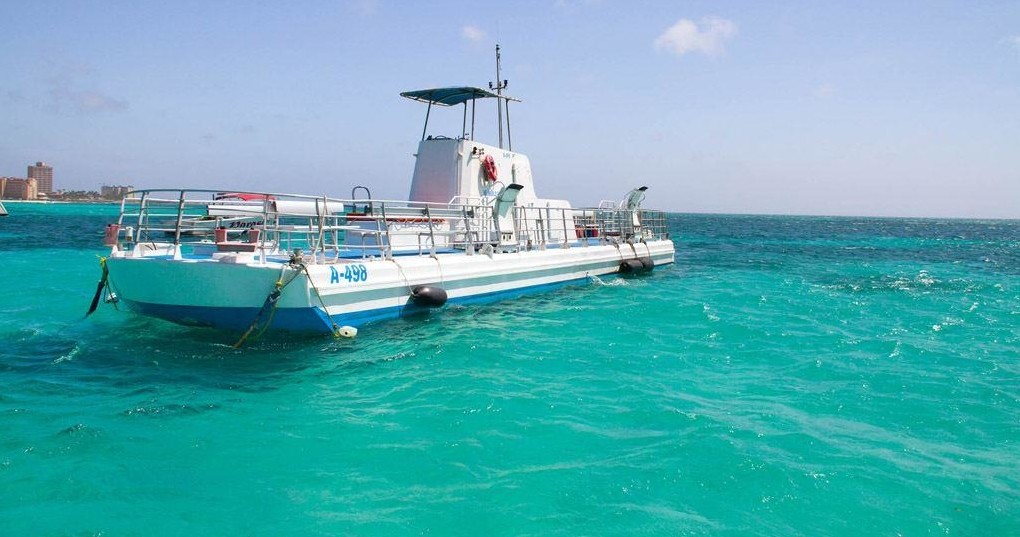 White boat floating on clear turquoise water under a clear blue sky.