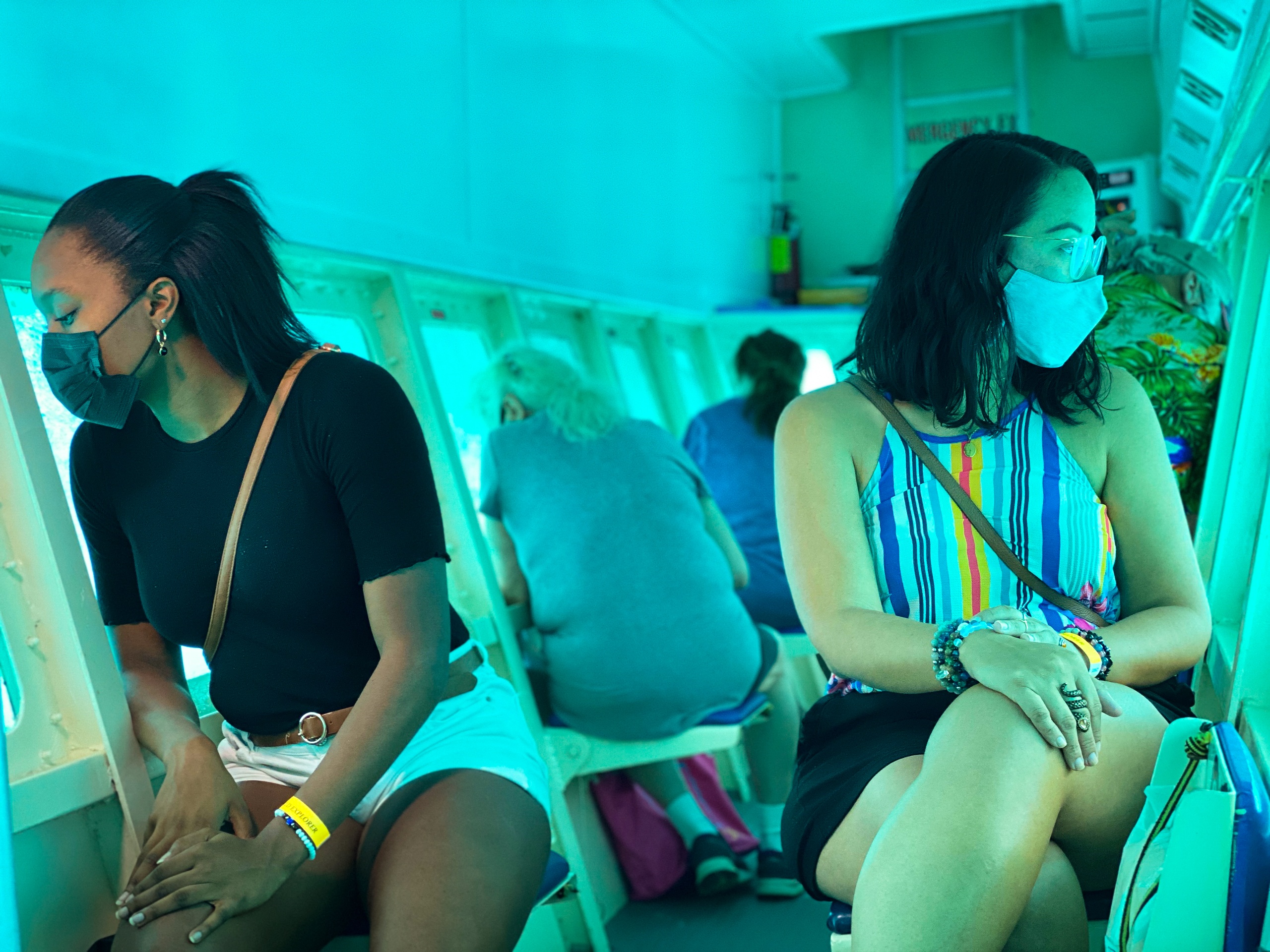 People wearing masks sit inside an underwater observatory, looking through windows.