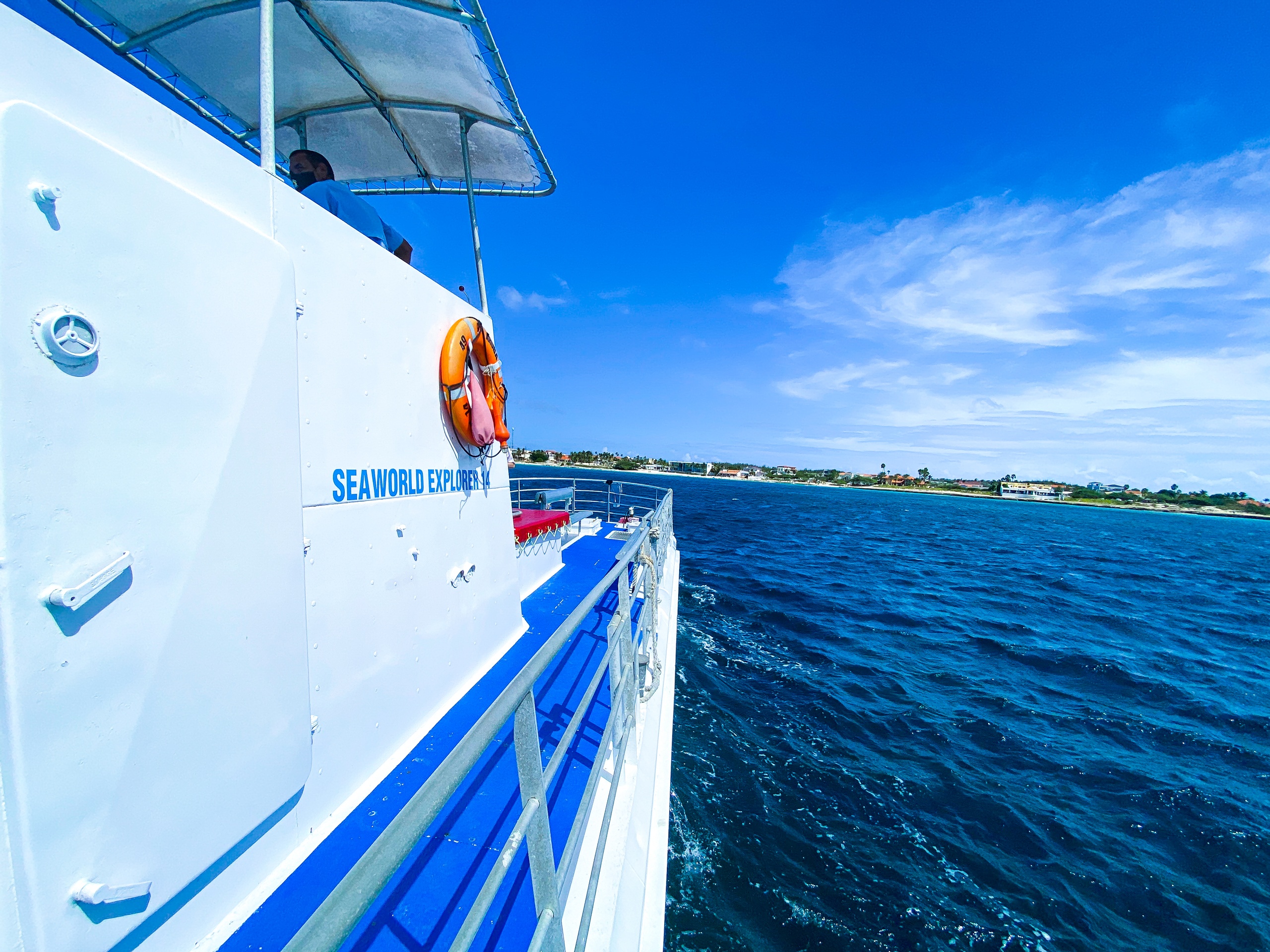 Boat on blue ocean with clear sky and distant coastline