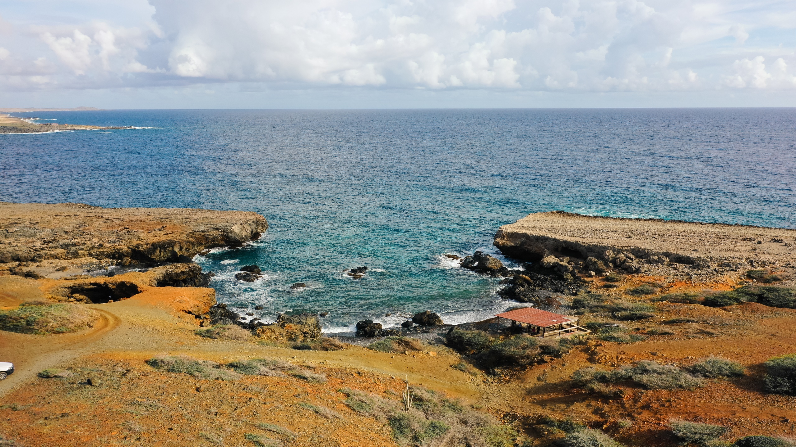 Coastal landscape with a rocky shoreline and small building near the sea.