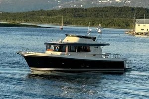 A motorboat cruising on a calm lake with mountains in the background.