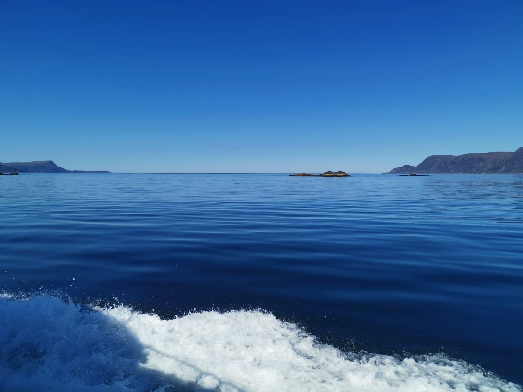 Calm blue sea with distant islands and a clear sky.