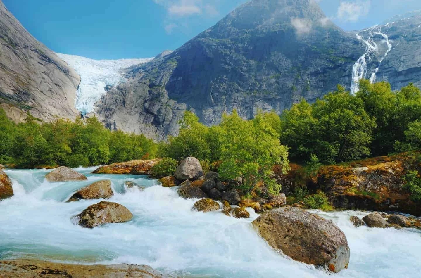 Mountain landscape with waterfall, glacier, and river.