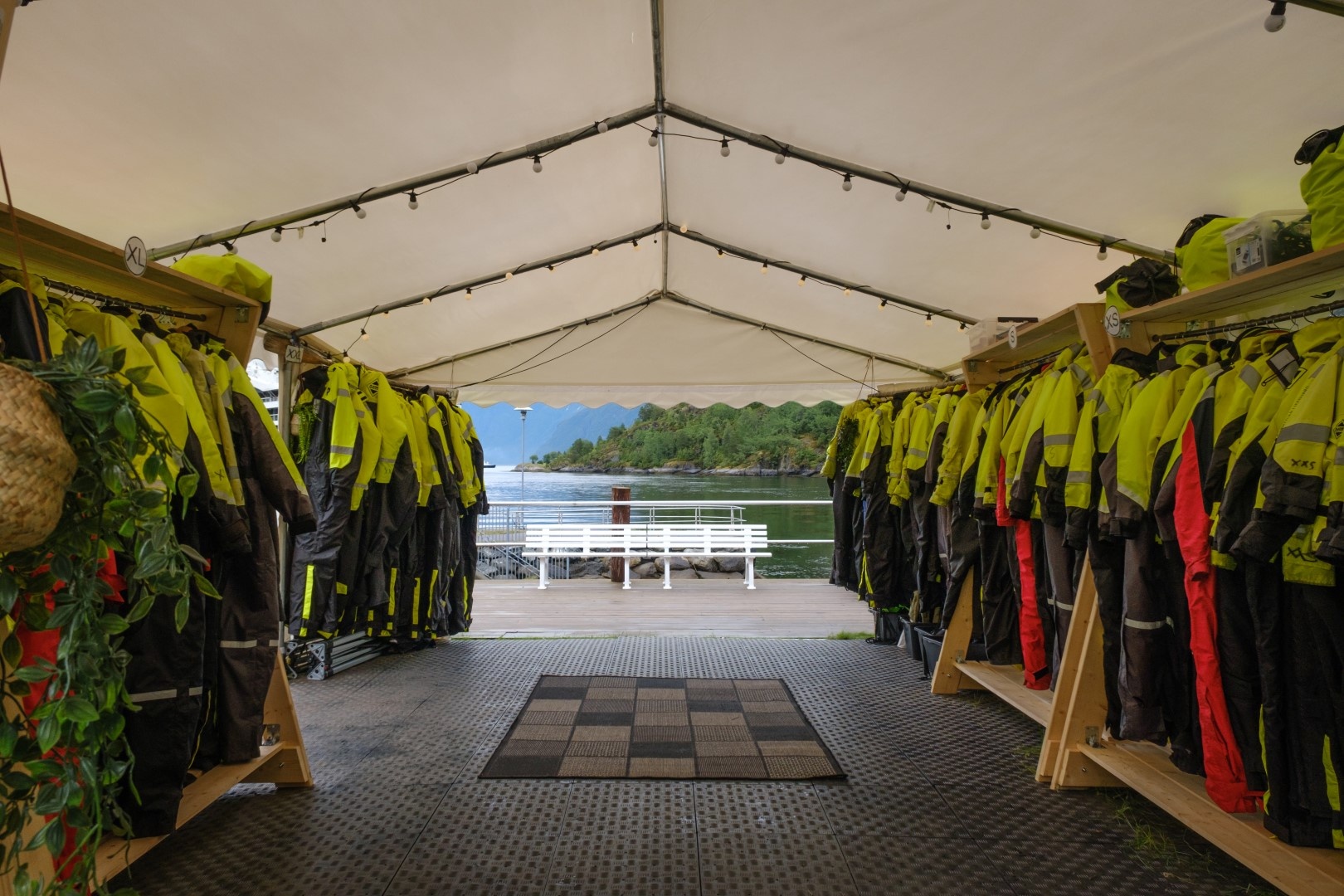 Tent with hanging yellow suits and a view of a pier and water.