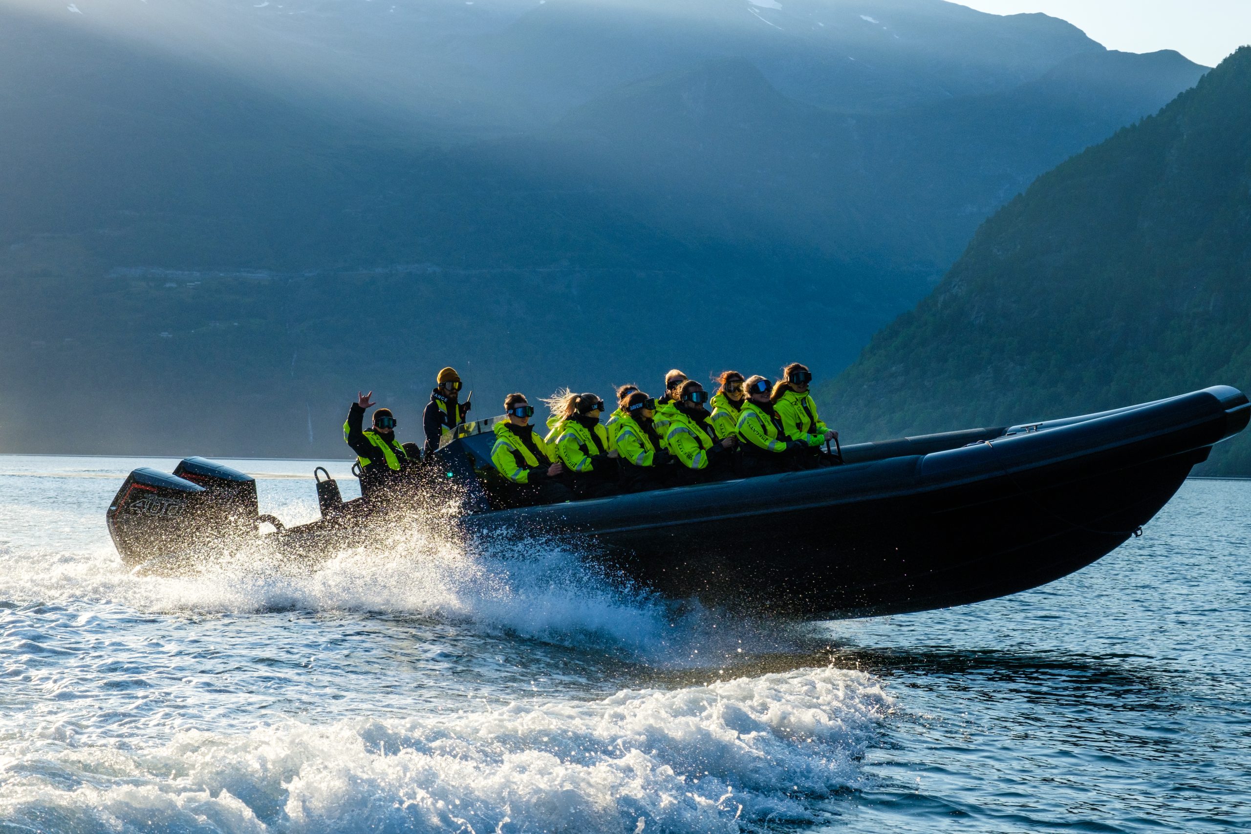 Speedboat with people in yellow jackets cruising in a scenic mountain lake.