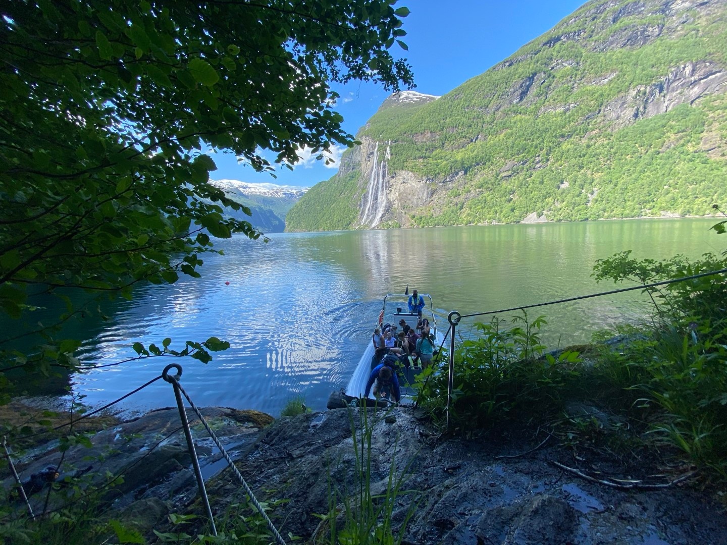 People on a raft at a scenic lake surrounded by mountains and trees.