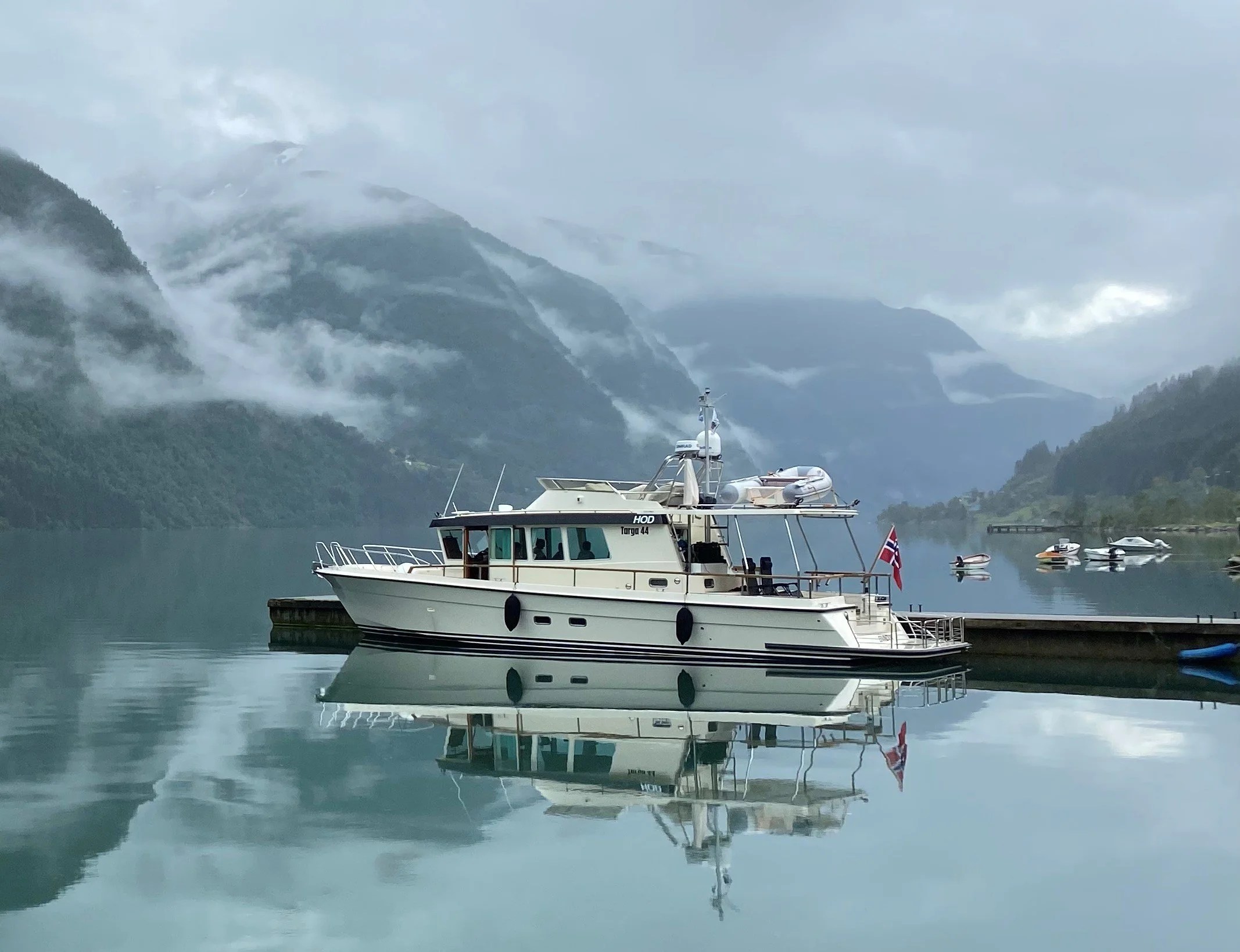 Boat docked on calm water with misty mountains in the background.