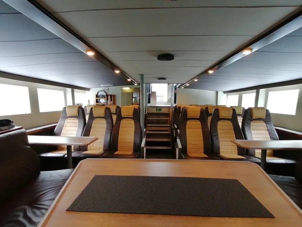 Interior of a ferry with empty rows of seats and tables