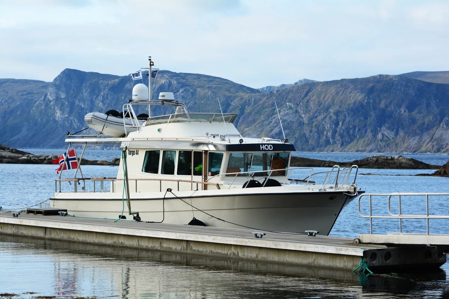 Boat docked at pier with mountains in the background.