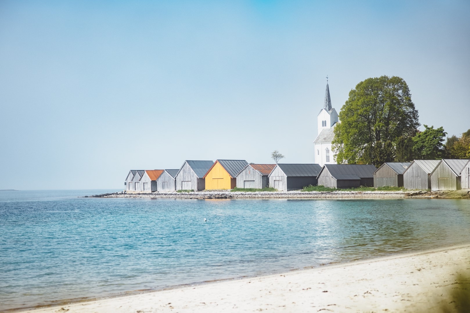 Beachfront with colorful houses and a church in the background.