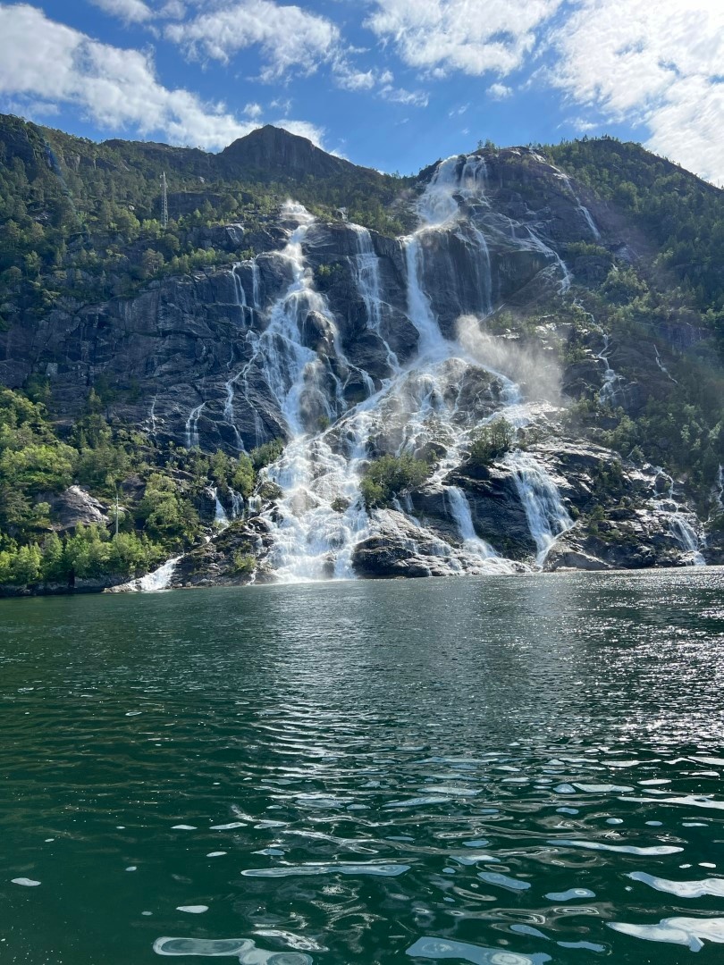 Waterfall cascading down a rocky mountain into a calm lake.