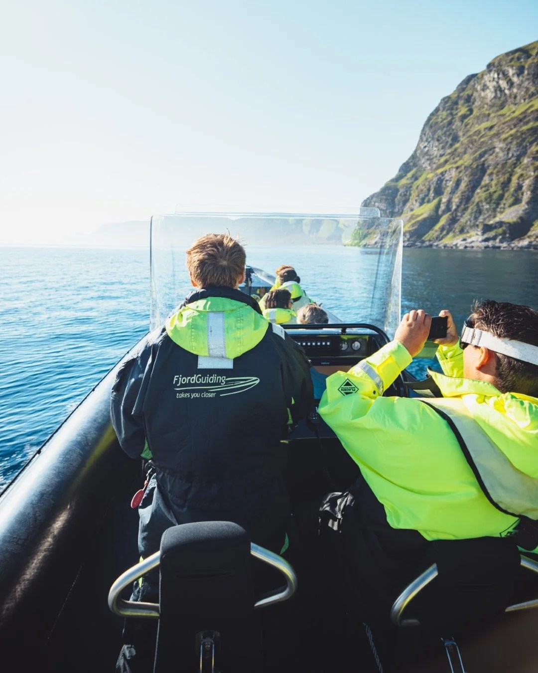 People on a boat tour with scenic coastal cliffs.