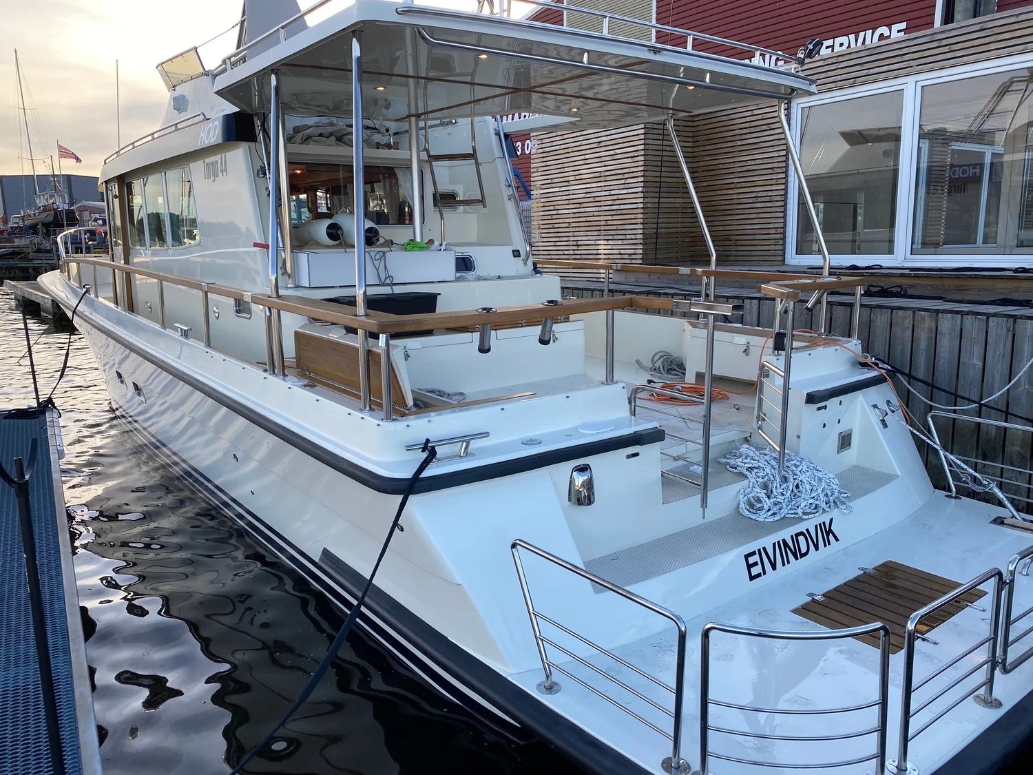 White motorboat docked at a marina with open aft deck.