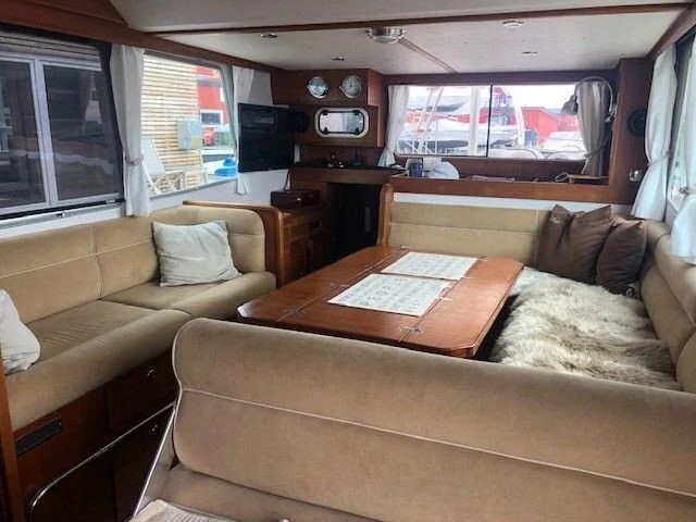 Interior of a boat with beige seating and a wooden table.