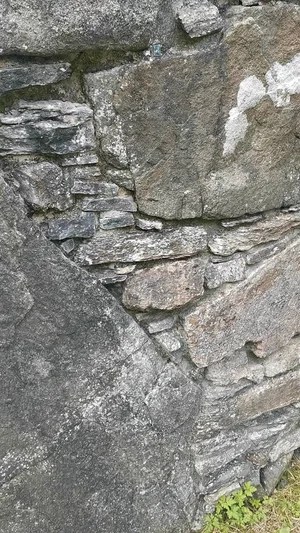 Close-up of a weathered stone wall with irregular rocks.