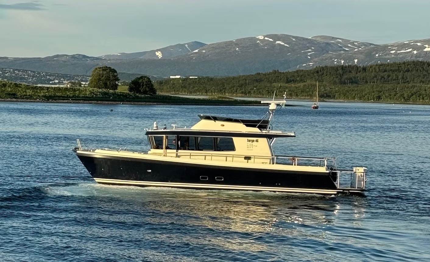 Motorboat on a calm lake with mountains in the background.
