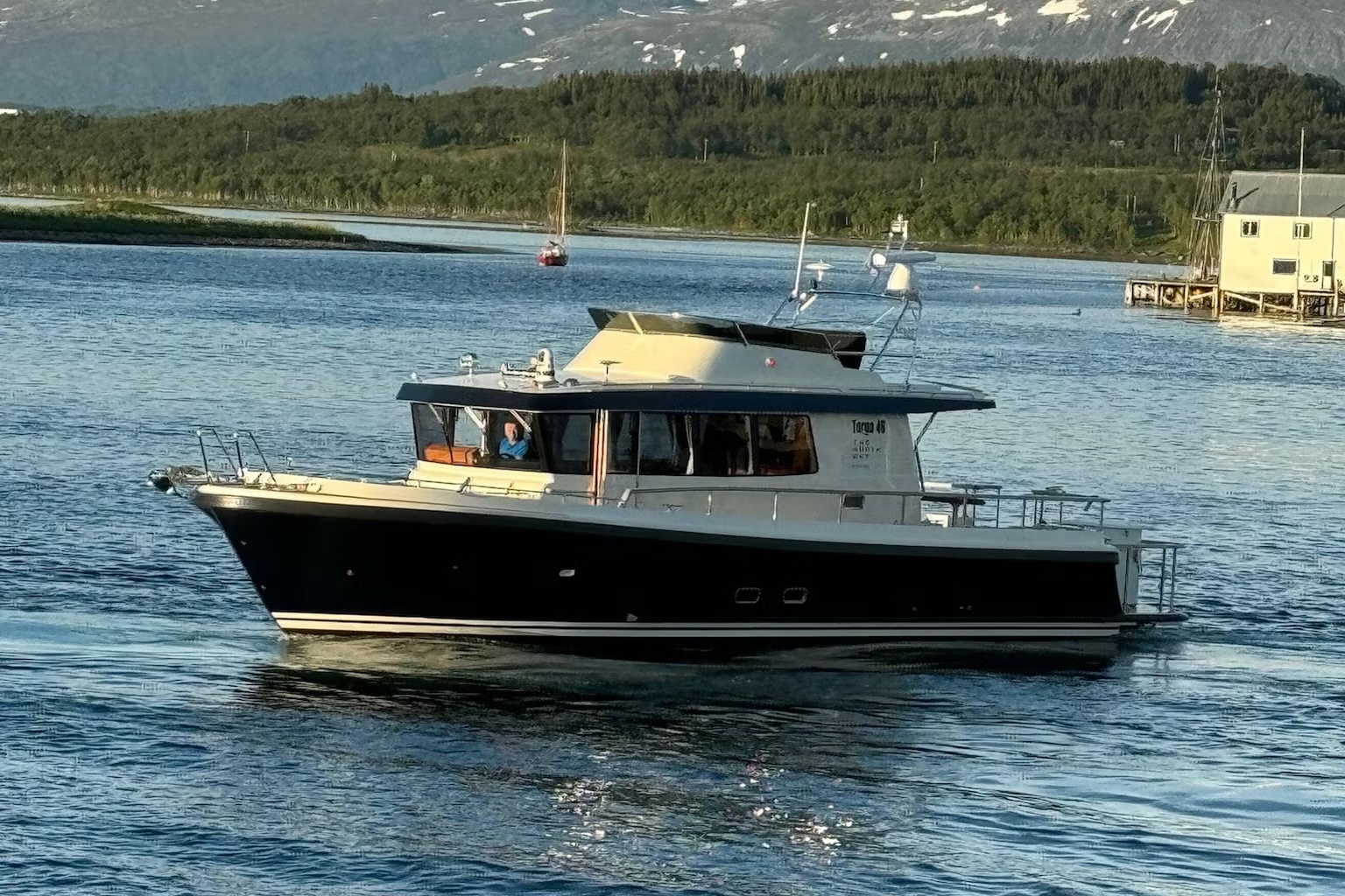 Motorboat cruising on a calm lake with forested hills in the background.