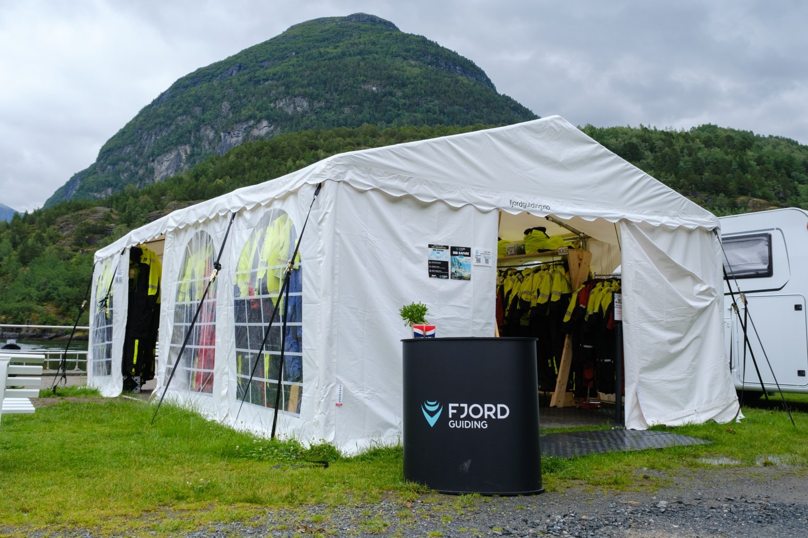 White tent with jackets inside, near a mountain landscape.