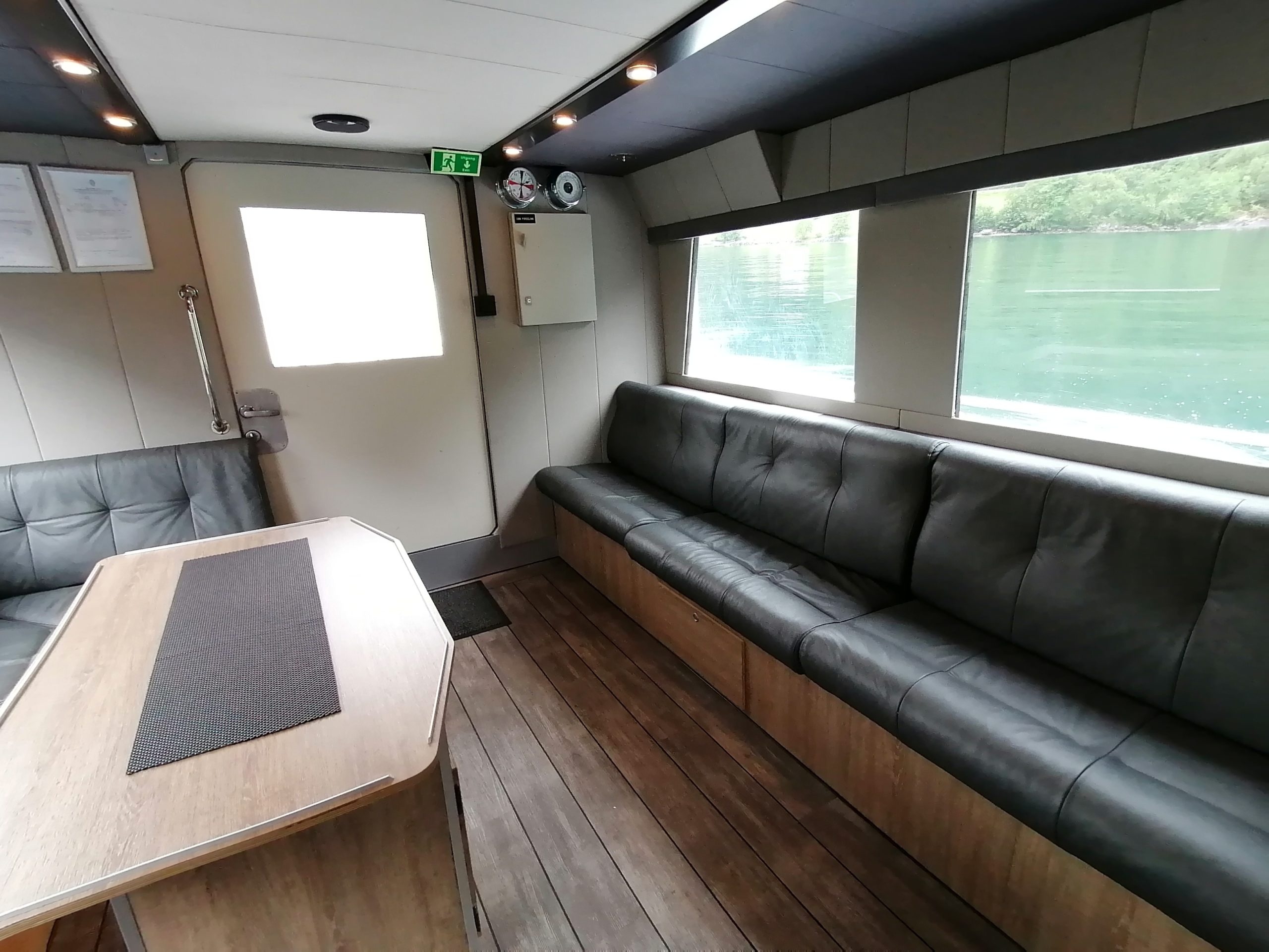 Modern boat interior with leather seats, wood floor, and large window.