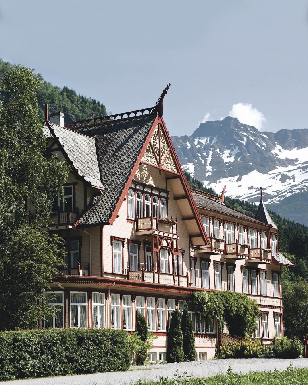 Historic wooden building with ornate roof, mountains in background.