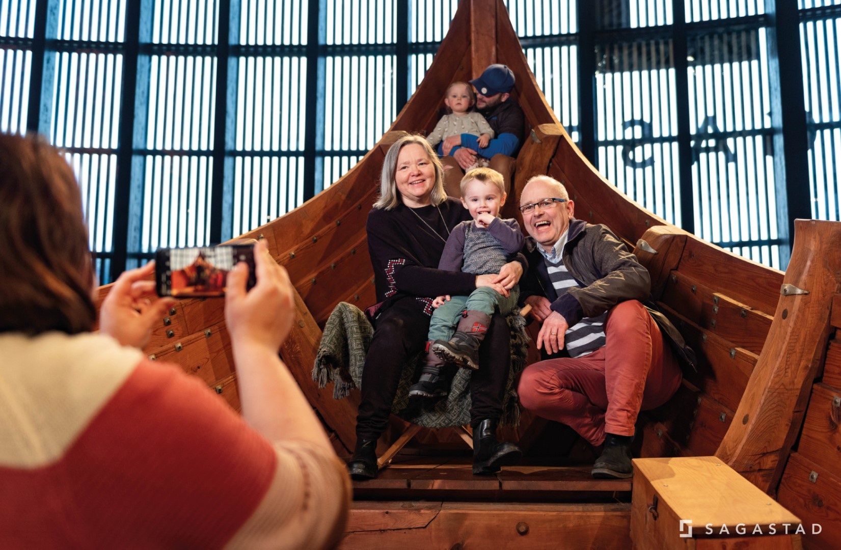 Family posing for a photo inside a wooden ship exhibit.