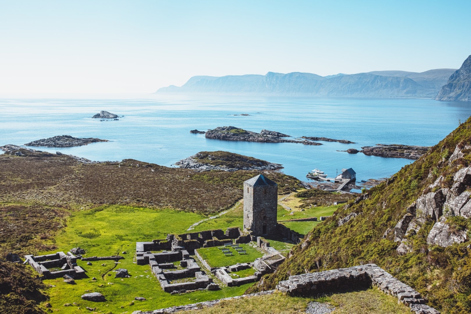 Rugged coastline with ancient ruins and stone tower by the sea.