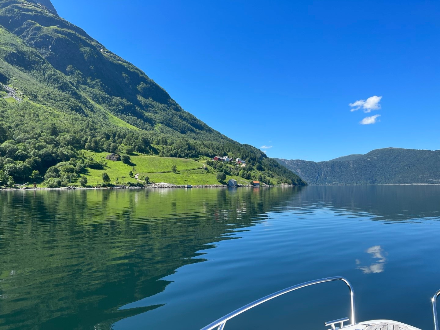 Boat on calm lake with mountain and clear blue sky.