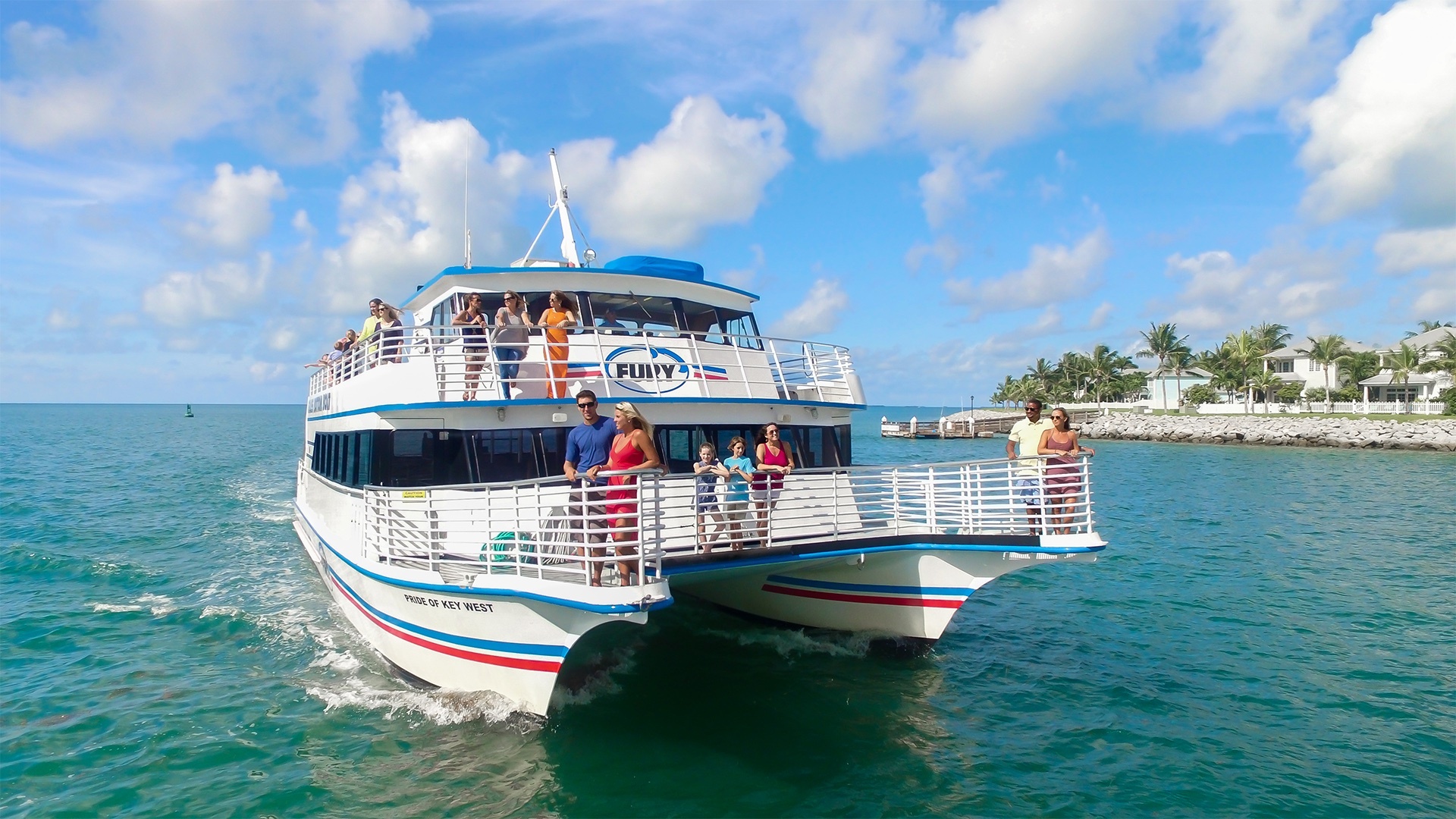 People on a two-level catamaran boat named Fury in a clear blue sea under a partly cloudy sky.