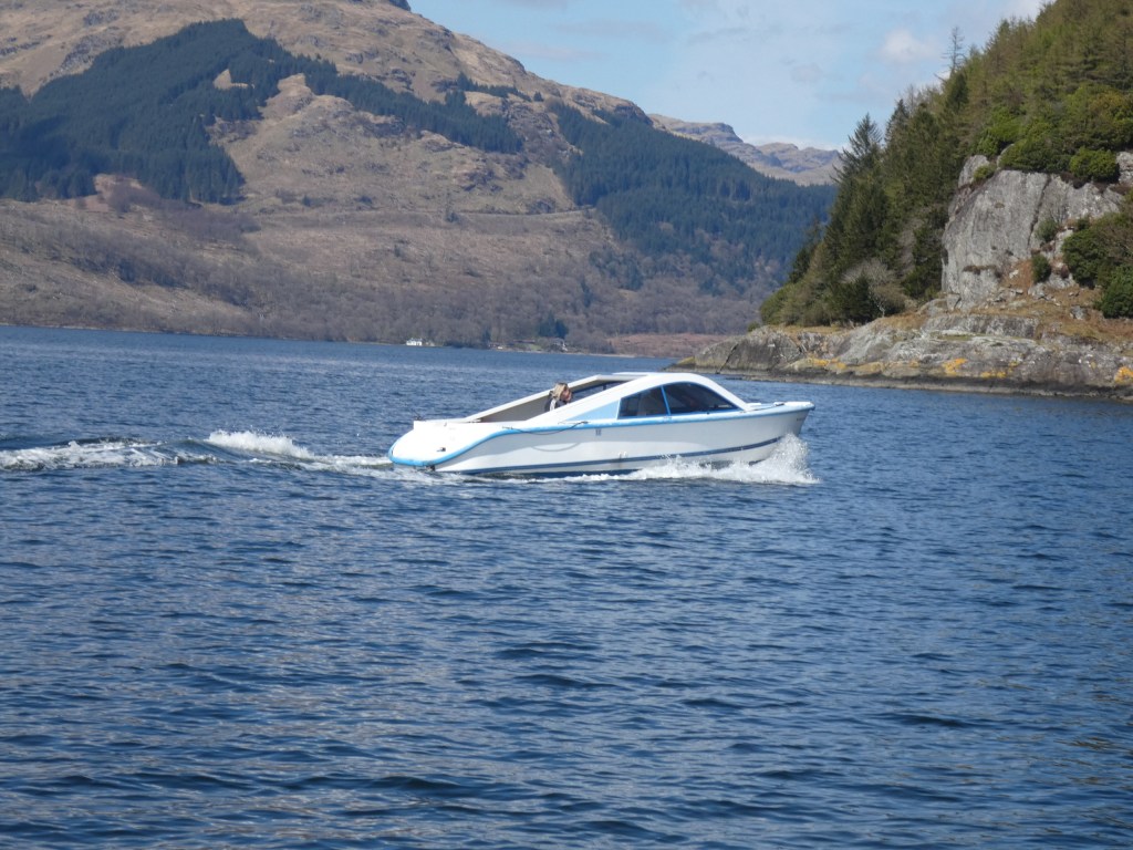 White motorboat on a lake with hills in the background.