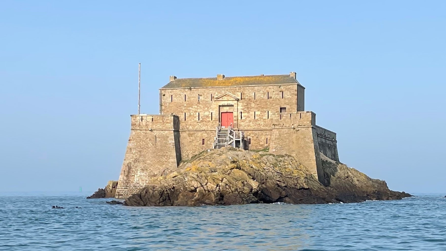 Stone fortress on a rocky island surrounded by calm sea.