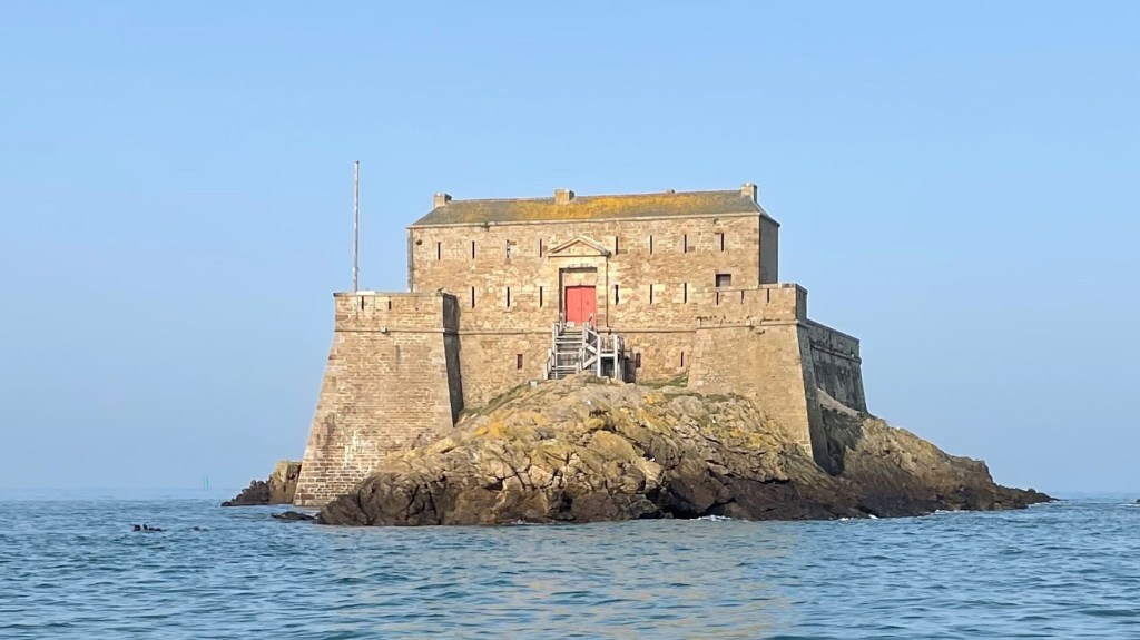 Stone fortress on a rocky island surrounded by calm sea.