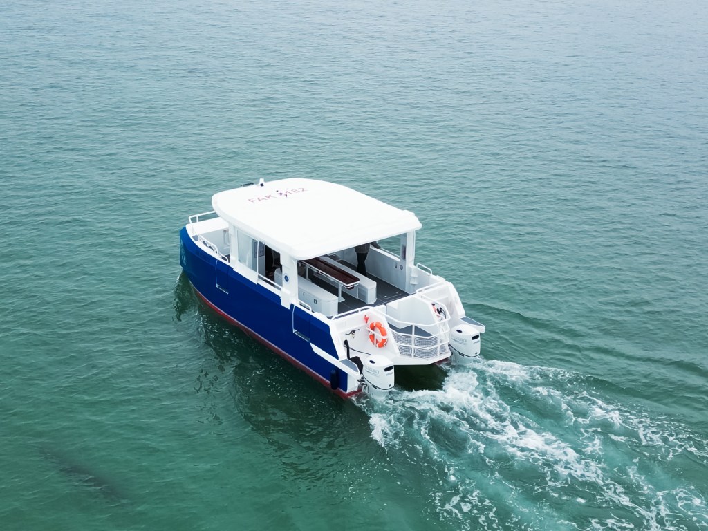Small blue and white boat cruising on calm teal water.