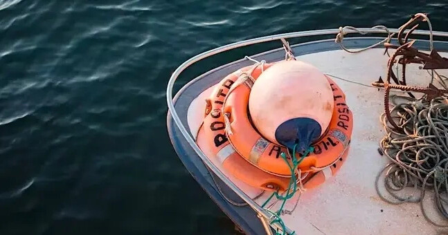 Lifebuoy and ropes on a boat deck over calm water.